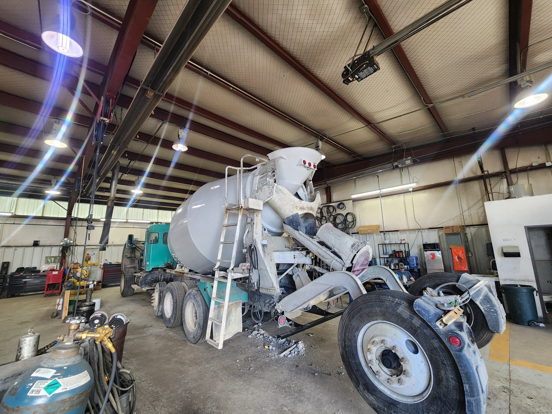 "Concrete mixer truck in a repair shop, receiving maintenance on its drum and other components to ensure optimal performance for heavy-duty construction tasks."