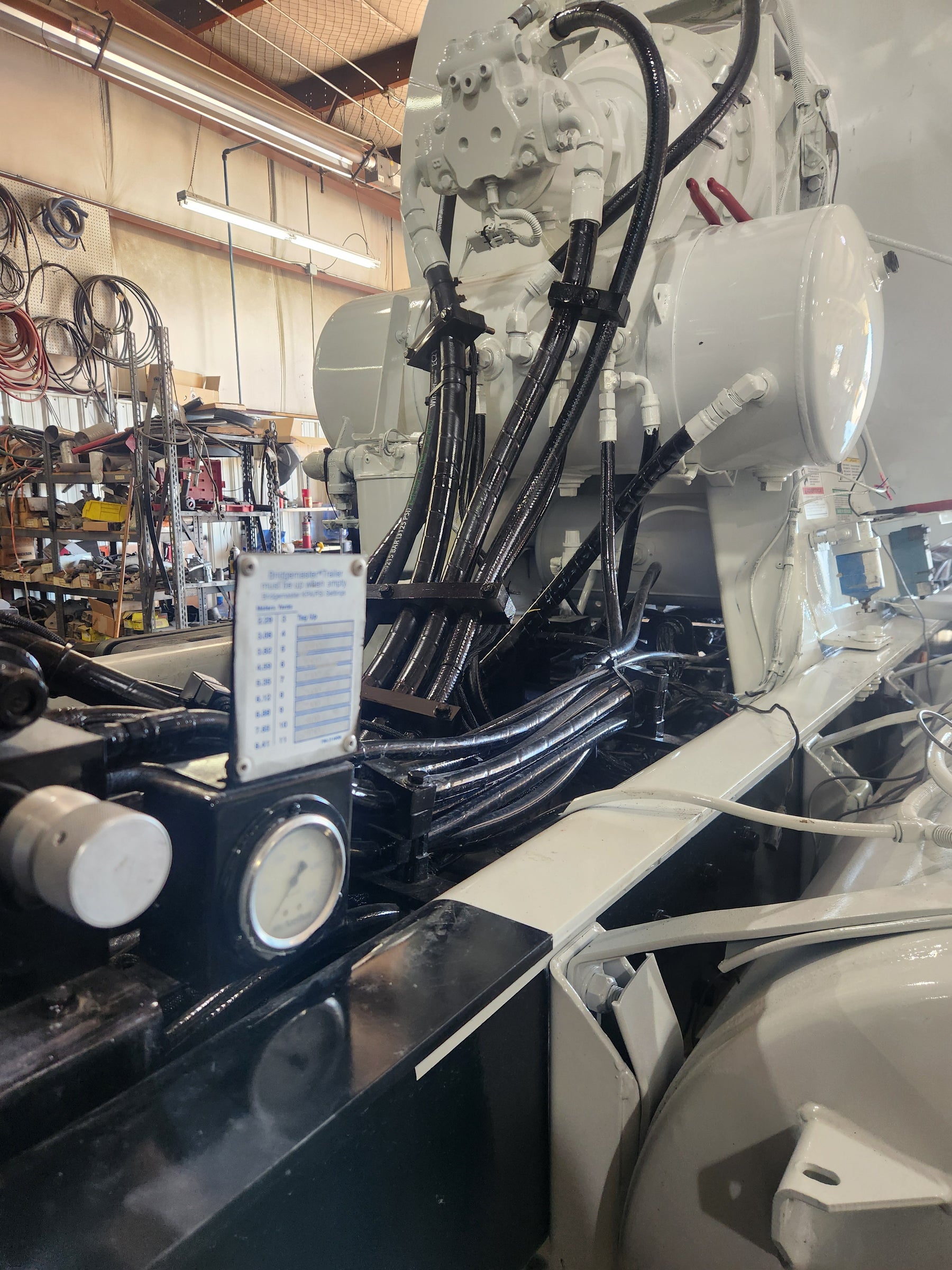 Close-up view of a freshly painted concrete mixer truck in a repair shop, showing detailed hydraulic hoses and components under bright workshop lighting.